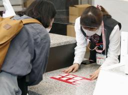 <p>　２０２２年用年賀はがきの販売が始まり、窓口で見本を見る女性＝１日午前、東京都千代田区</p>