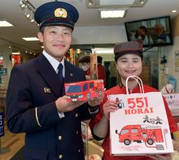<p>　消防車を模した紙箱に豚まんを入れた商品を手にする大阪市消防局予防課の長沢宏太さん（左）＝１日午後、大阪市</p>