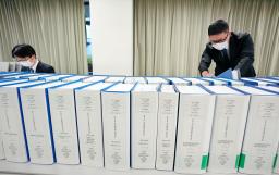 <p>　２０２０年分の政治資金収支報告書（総務相所管の中央分）。奥はチェックする職員＝総務省</p>