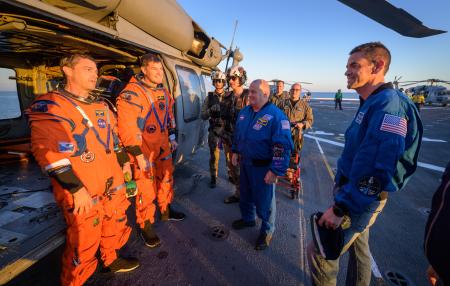 　地球に帰還し、米軍の船上でＮＡＳＡのアイザックマン長官（右端）と話すワイズマン飛行士（左端）とハンセン飛行士（左から２人目）＝１０日（ＮＡＳＡ提供）