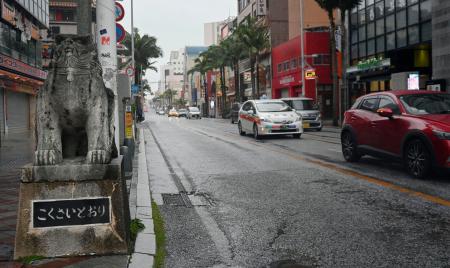 <p>　雨と強い風の中、国際通りを走行する車＝１日午前、那覇市</p>