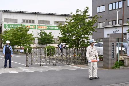 　クマに従業員が襲われた「福島製鋼」事業所の入り口付近で警戒する警察官や関係者＝２日午前８時５４分、福島市
