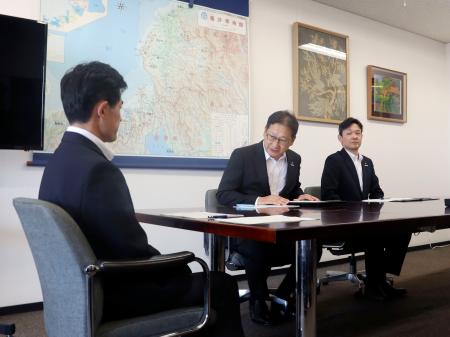 <p>　福井県の坂本裕一郎防災安全部長（左）と面会する関西電力の高畠勇人原子力事業本部長代理（中央）＝１２日午後、福井県庁</p>