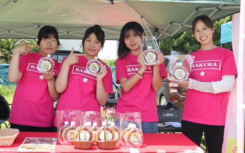 「白子たまねぎ祭り」でお披露目されたソース「たまんねーぎ」を手にアピールする(右から)片岡さん、露崎さん、鶴岡さん、佐藤さん=5月10日、白子町