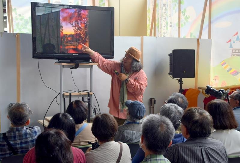 小湊鉄道沿線で撮影した作品について解説する中井さん＝市原市の夢ホール