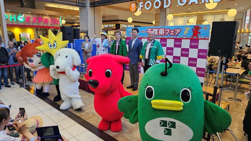 ご当地キャラとともに、県産食品をPRする熊谷知事(後列右から2人目)。セレモニーにはタレントで魚類学者のさかなクン(同4人目)も参加した=13日午後、習志野市