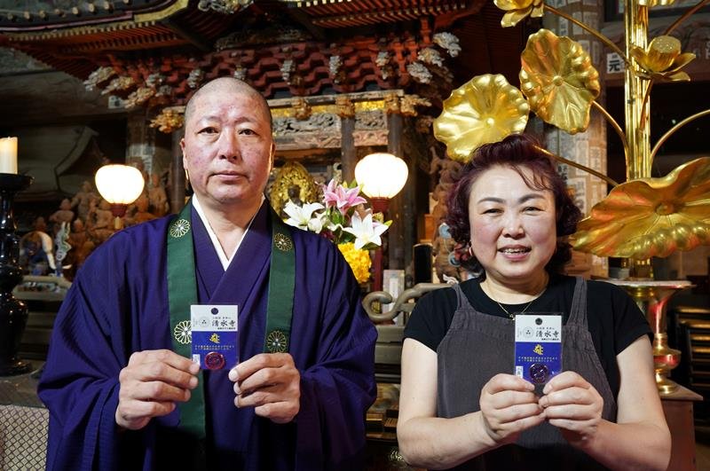 祈とう後のピンバッジお守りを手にする、清水寺の井上住職（左）と妻の恵津子さん＝いすみ市