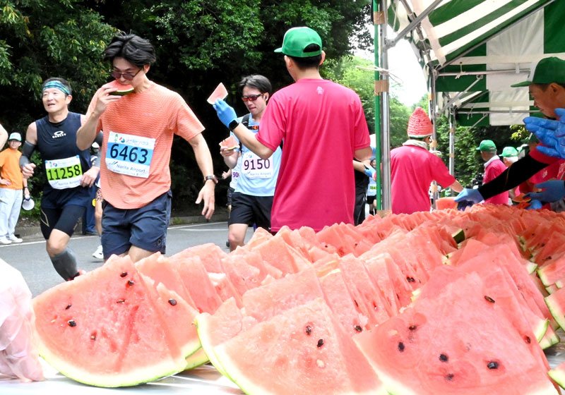「給スイカ所」で特産のスイカを頬張るランナー＝富里市