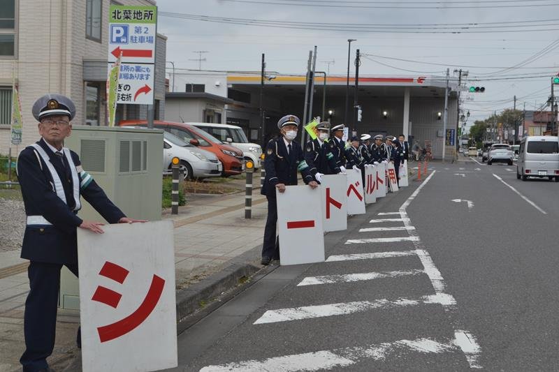 「シートベルト着用!」のプラカードを掲げ、安全運転を呼びかける佐倉交通安全協会の会員ら=4月、八街市