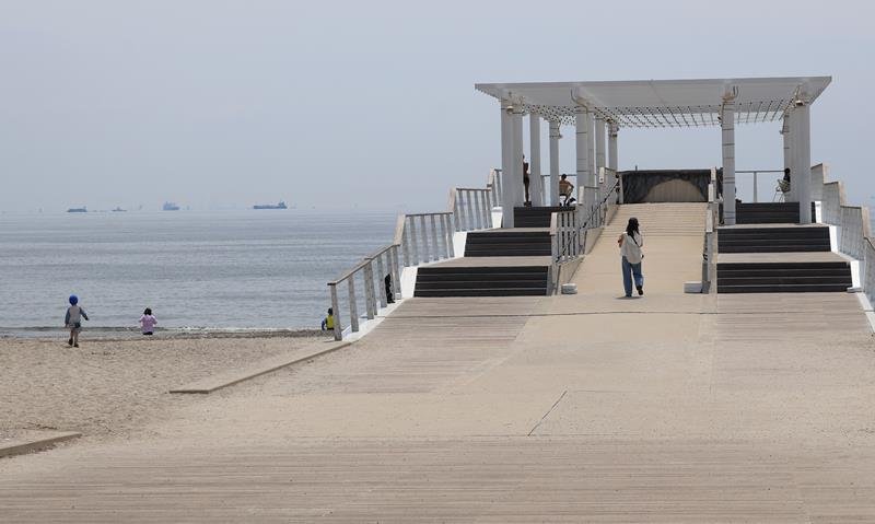 千葉市内で気温が上昇した１９日、いなげの浜ではウッドデッキで過ごす人だけでなく、早くも海に入る人の姿があった＝同市美浜区