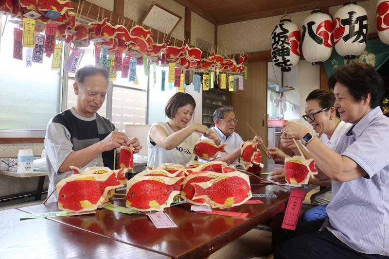 杉田会長が制作した鯛ちょうちんに持ち手の竹を付ける氏子ら＝茂原市