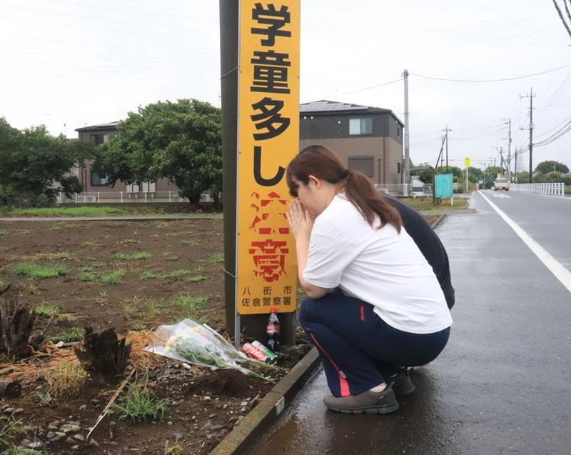 事故現場に花を供える夫妻=28日午前10時15分ごろ、八街市