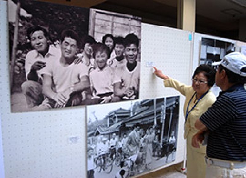 長嶋氏が大学２年生のころ、小学校の同窓生が地元でそろった際に撮影された写真について説明する吉田会長（長嶋氏は前列左、隣の女性は当時の吉田会長）＝２３日、佐倉市王子台のレイクピアウスイ３階