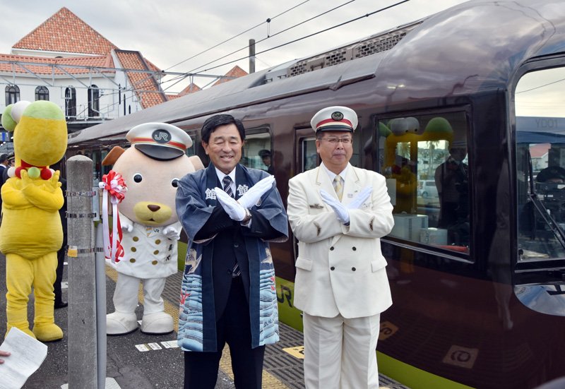 「Ｘポーズ」を披露する鈴木駅長（右）と金丸市長＝館山市のＪＲ館山駅

