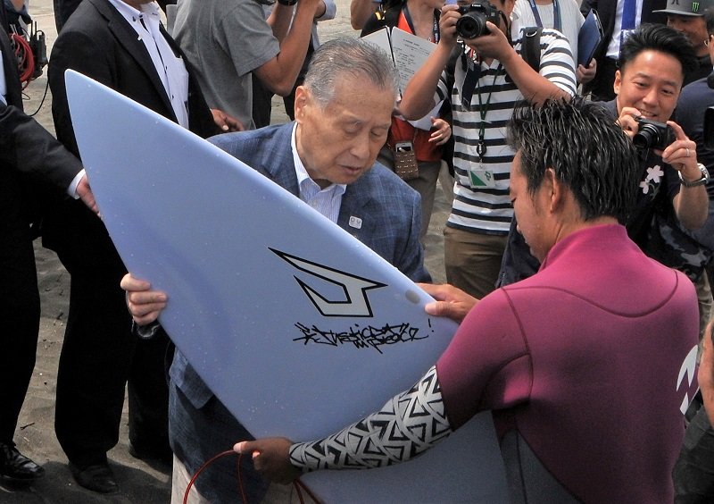 東京五輪サーフィン会場の釣ケ崎海岸を視察し、サーファーからボードの説明を受ける森喜朗会長＝２０１７年６月、一宮町