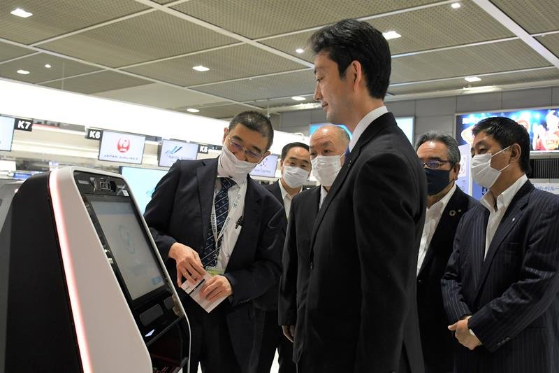 実証実験中の顔認証による搭乗手続きシステムを体験する熊谷知事（中央）＝２０日、成田空港
