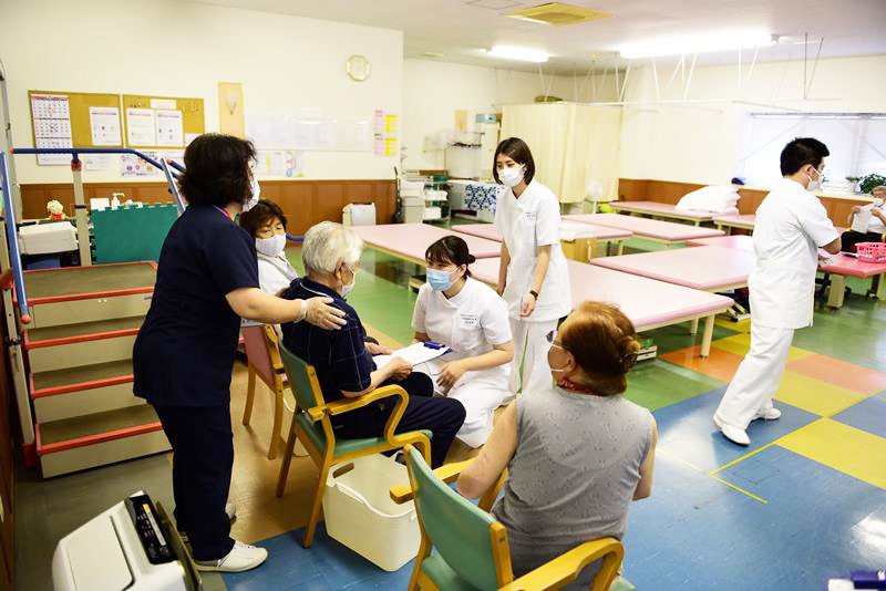 ワクチン接種後の高齢者の体調確認を行う学生ら＝１９日、香取市 