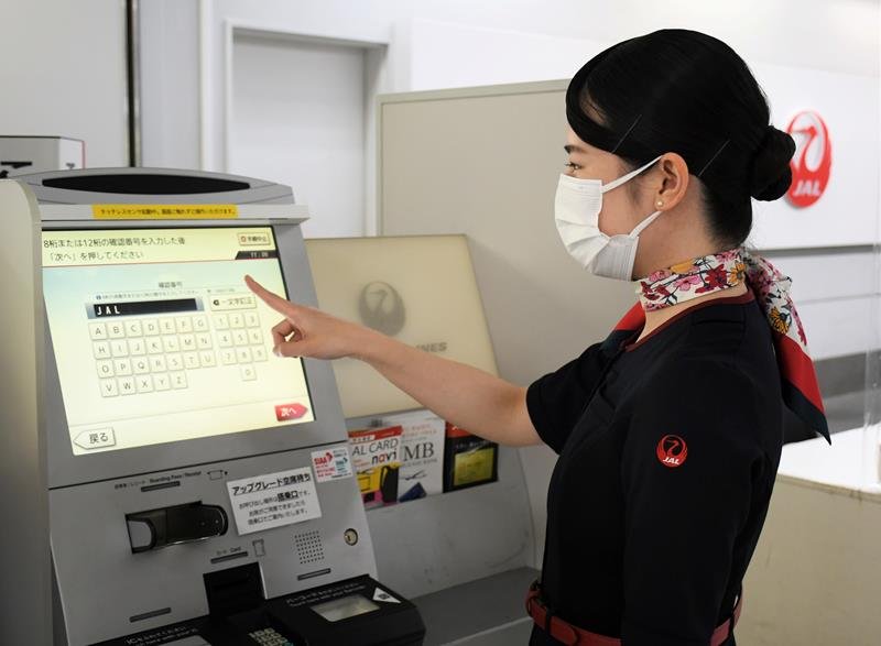 非接触で操作できる自動チェックイン機のデモンストレーションをする地上係員＝成田空港
