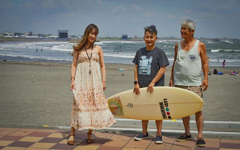 サーフィン競技が行われている会場が、遠くに見えるいすみ市の太東海岸で（右から）泉健二さんと山田浩之さんを訪ねた雨宮処凛さん（共同）
