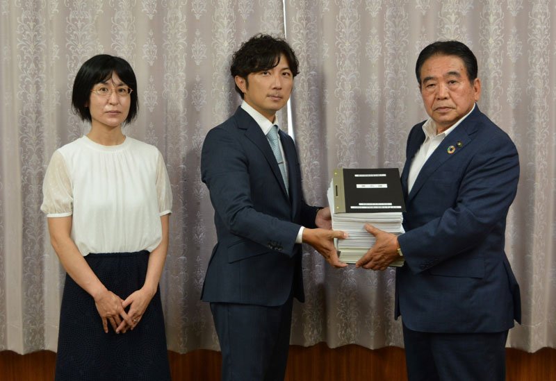 １万人を超える署名とともに要望書を板倉市長（右）に提出する大野代表（中央）＝印西市役所
