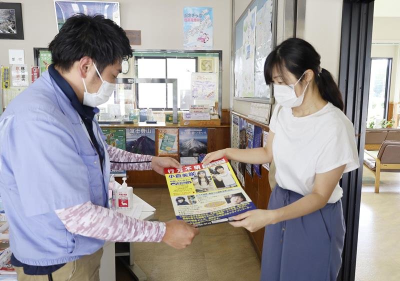 小倉美咲さんの情報提供を呼び掛けるポスターを手渡す母とも子さん（右）＝１１日午後、山梨県鳴沢村の道の駅(共同)
