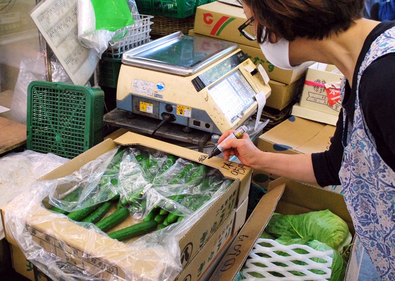 キュウリの値段を書く青果店員。通常の倍ほどの１本９５円（税抜き）に高騰している＝１６日午後、千葉市中央区