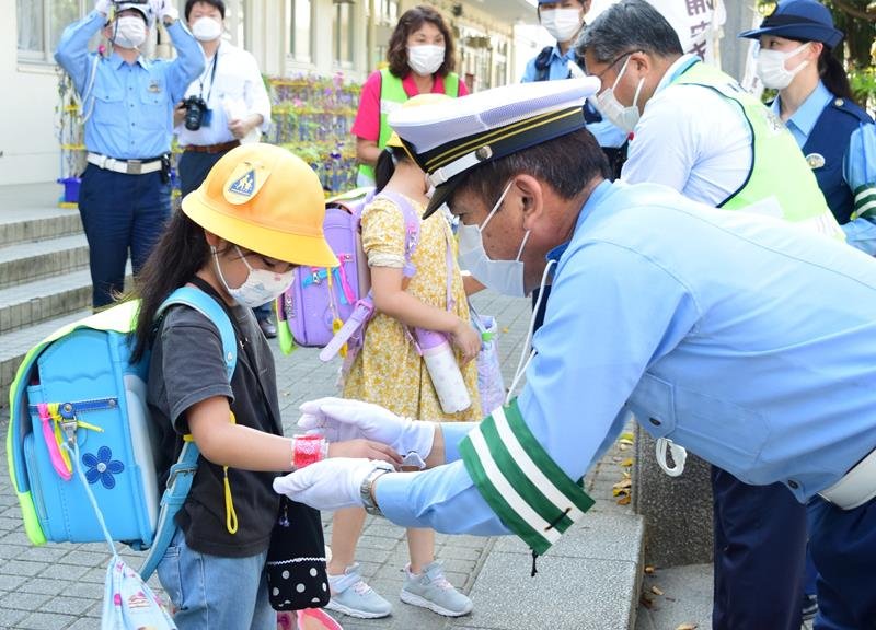 児童に反射材を取り付ける有賀署長（右）ら＝浦安市
