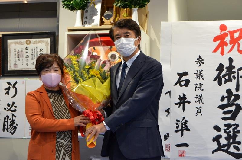 ５度目の当確の知らせを受け、支持者から花束を受け取る斎藤氏（右）＝３１日、流山市

