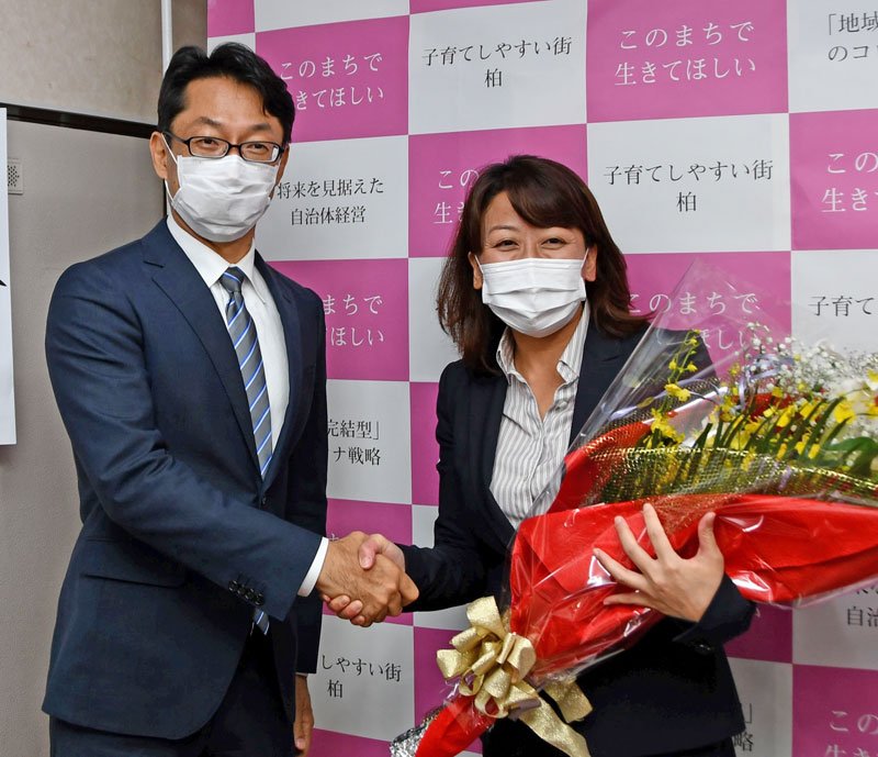 駆け付けた秋山浩保・現市長（左）から祝福を受ける太田氏＝１日未明、柏市