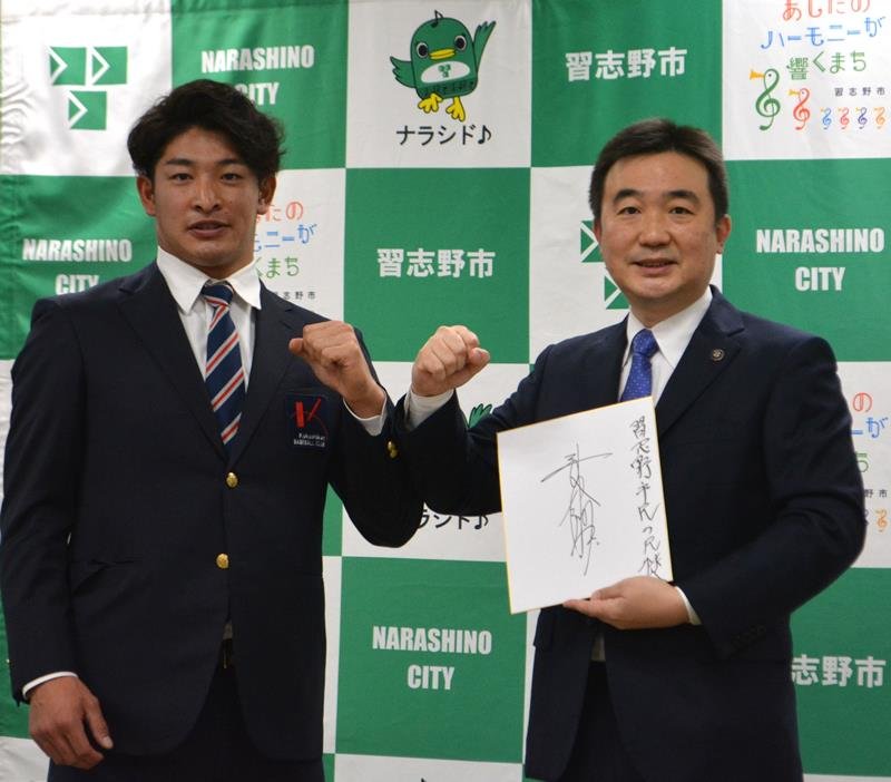 千葉ロッテ入団を報告し、記念のサイン色紙を宮本市長（右）に手渡して意気込む習志野高出身の池田選手＝３０日、習志野市役所

