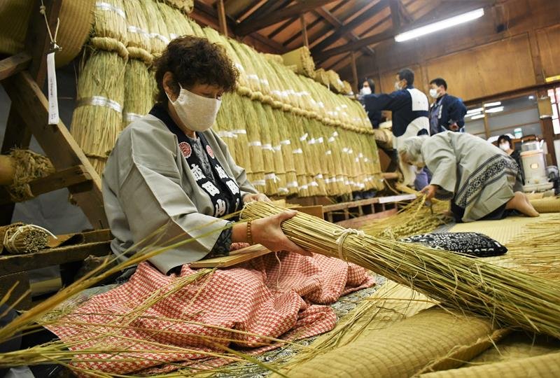 わらを編み込んで正月の飾りを作る成田山新勝寺の奉仕員＝１日、成田市
