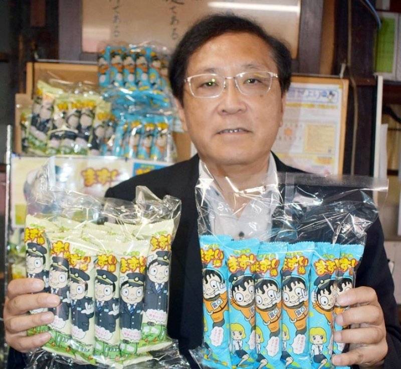 「まずい棒」を手にする竹本社長＝２０１９年６月