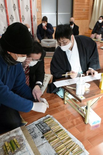 竹筒に入った米や小豆の具合を確かめる松山義仁宮司（右）ら＝１５日、匝瑳市
