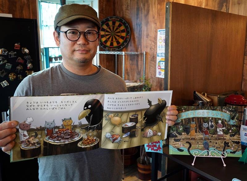 絵本「さんびきのさすらいねこ」を持つ土田代表＝大多喜町