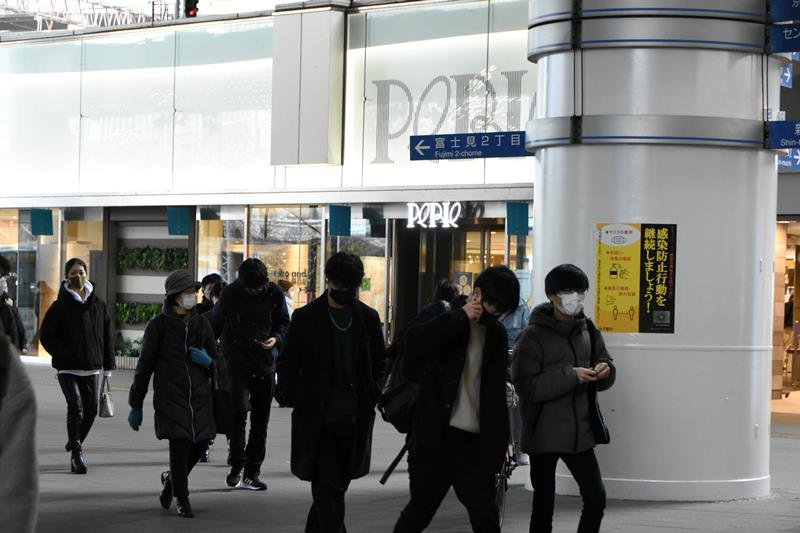 感染防止行動を訴えるポスターが張られたＪＲ千葉駅前。マスクを着けた人が行き交う＝１９日午後、千葉市中央区
