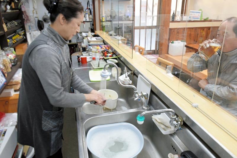 断水が解消し、水道水で調理器具を洗う居酒屋の女性＝２２日午後、旭市
