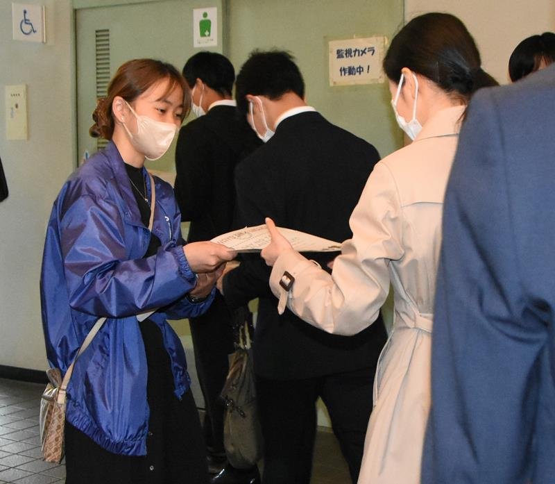 紙製のクリアファイルを新入生に手渡す「環境ＩＳＯ学生委員会」メンバー＝５日午後、千葉市中央区の千葉ポートアリーナ

