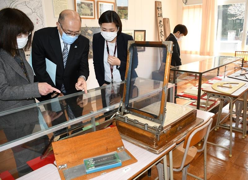 旧滑河小学校の校舎に設けられた展示室の内覧会で、かつて教室で使われた用具を見学する関係者＝成田市

