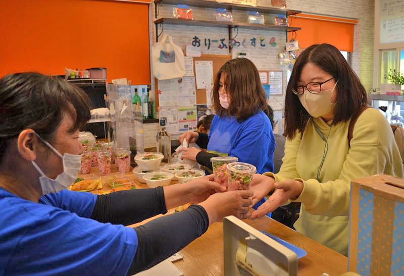 ビーツを使ったウクライナ風のポテトサラダを受け取る客（右）＝１７日午後１時ごろ、千葉市稲毛区
