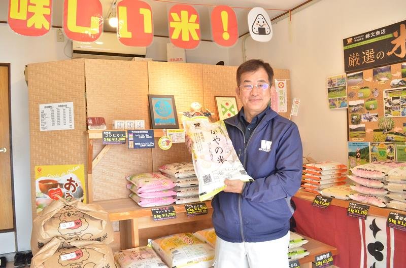 「かやの米」を手にする加藤社長。本社の店頭にはさまざま品種の米が並ぶ＝大網白里市
