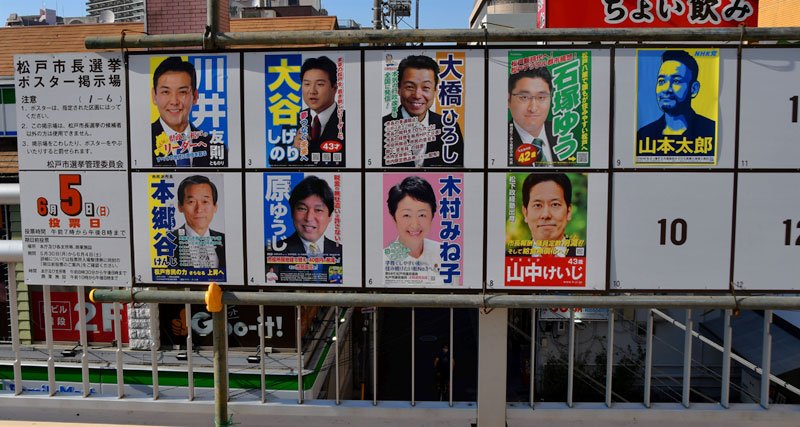 過去最多の立候補者９人のポスターが並ぶ掲示板＝ＪＲ松戸駅前
