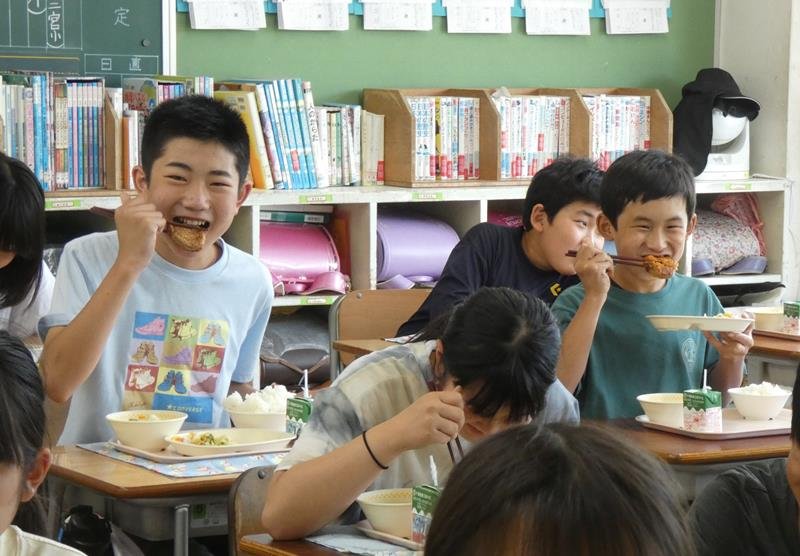 白子たまねぎを使ったハンバーグを頬張る６年生＝白子町立関小