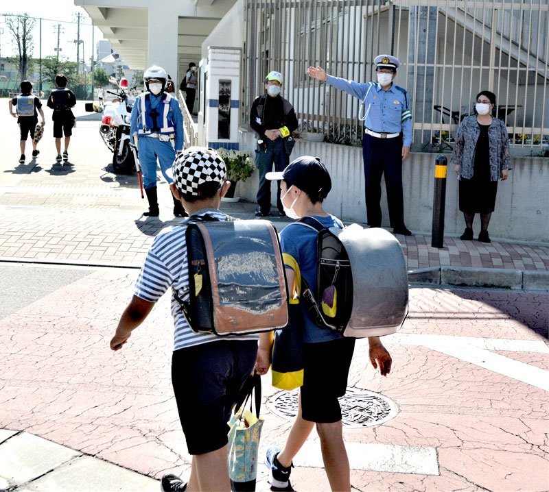 白バイ隊員らと一緒に船橋小の校門前に立ち、登校児童を見守る杵渕署長（右から２人目）と松本教育長（右）＝２７日朝、船橋市
