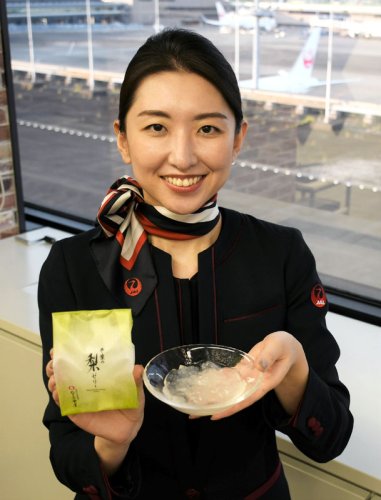 日本航空の機内で提供される米屋の「千葉の梨ゼリー」を紹介する鈴木さん＝成田空港