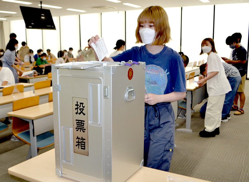 本物の投票箱などを使って行われた模擬投票で、１票を投じる学生＝５日、千葉市中央区