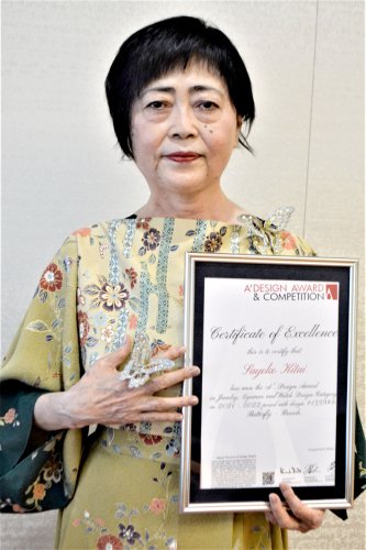 受賞した蝶の立体刺しゅうブローチを披露する北井さん＝船橋市役所