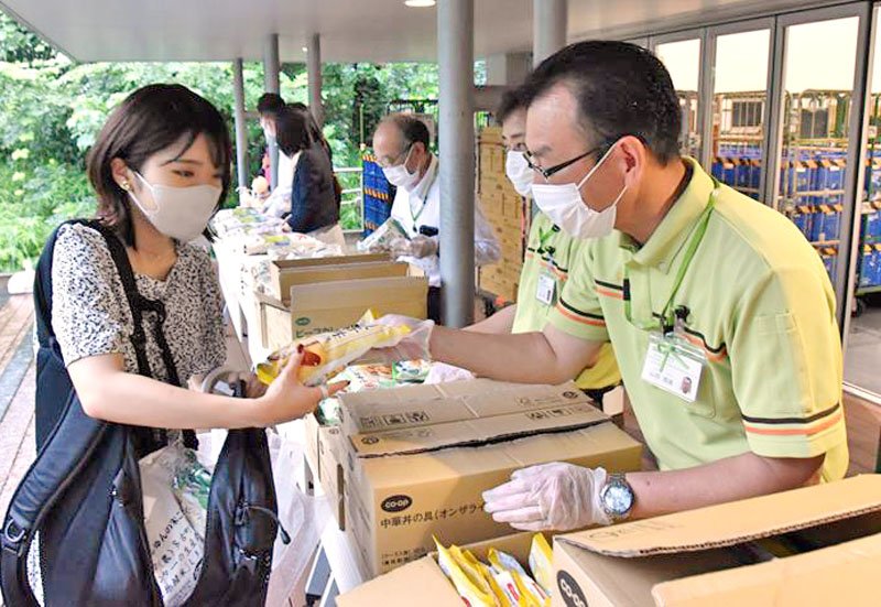 コープのスタッフ（右）から食料品を受け取る学生＝１５日、千葉市稲毛区