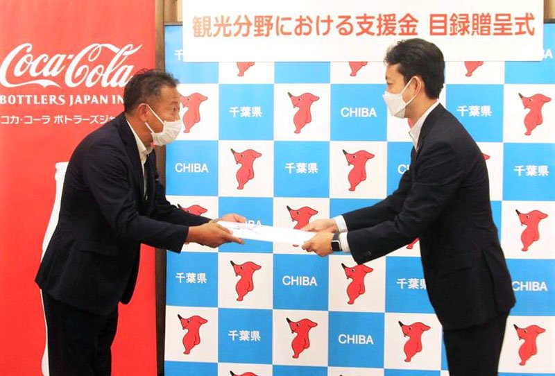 熊谷知事（右）に目録を手渡すコカ・コーラボトラーズジャパンの市川関東地区統括部長＝２２日、千葉県庁
