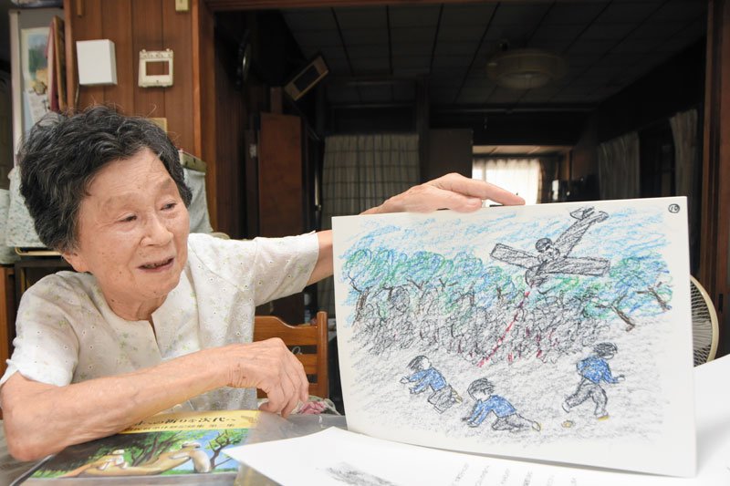 自身が作成した戦争体験の紙芝居を見ながら、当時のことを回想する花沢さん＝千葉市中央区