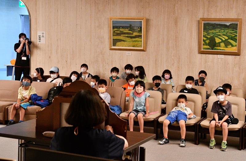 お化けの紙芝居の読み聞かせに耳を傾ける子どもたち＝多古町
